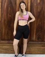 Top deportivo rosa con breteles anchos y contorno negro, con push up removible y banda inferior con la inscripción "THE HONEY".