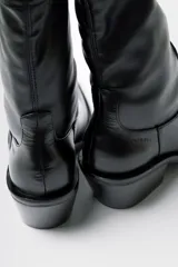 Bota de caña media estilo western, confeccionada en cuero negro, con taco cuadrado y punta cuadrada.