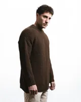 Buzo unisex de tejido de punto grueso en lana merino, color rojo, con cuello redondo y diseño de calce relajado. Presenta un detalle bordado a mano en contraste en la manga.