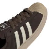 Championes Adidas Superstar II color marrón oscuro con las icónicas tres tiras laterales en color crema. Presenta la clásica puntera de goma reforzada y suela de plataforma en tono beige.