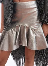 Minifalda de cuero color marrón oscuro, con fajón en la cintura y volados en el ruedo.