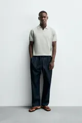 Jersey de punto color verde oliva, de calce relajado (relaxed fit), con cuello solapa y abertura frontal en forma de V. Es de manga corta y presenta acabados en rib en puños y ruedo.