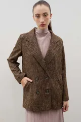 Blazer de lana con diseño bicolor, cuerpo en color negro y mangas en color crema. Presenta un corte holgado, cierre cruzado con doble botonadura y solapas amplias en contraste.