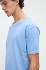 Remera de manga corta color blanco off-white, de calce clásico en tejido jersey de algodón. Presenta un gran diseño estampado en la espalda con un recuadro celeste que incluye las leyendas "WILD OCEAN" y "SALTY SOUL" junto con gráficos de olas y estrellas en tonos rosados y amarillos.