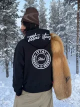 Hoodie negro con capucha, diseño estampado en la espalda con el logo de la marca dentro de un círculo de laureles y texto en la parte posterior de la capucha.