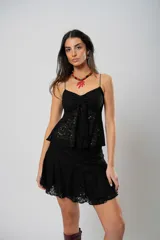 Pollera corta de encaje negro con diseño de volados escalonados y terminación con borde festoneado.