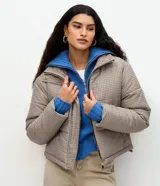 Campera puffer Marfinno con estampa de cuadros mini en tonos beige y negro, de corte recto, cuello alto y cierre frontal con cremallera. Cuenta con mangas largas y forro interior.