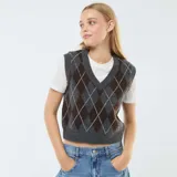 Sweater sin mangas de punto con cuello en V y estampado de rombos en tonos gris y marrón, que incluye una camiseta básica de manga corta en color blanco debajo.