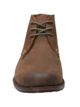Bota tipo chukka de cuero engrasado color marrón, con cordones y suela de goma. Presenta un diseño urbano con costuras reforzadas y detalle de logo bordado en el lateral.