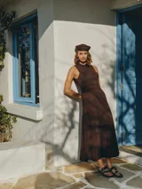 Vestido largo marrón de tejido con caída fluida, diseño sin mangas, cuello redondo y silueta entallada en la parte superior que se amplía suavemente hacia el ruedo.