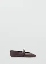 Zapato plano estilo Mary Jane color marrón, confeccionado en piel de ovino, con punta fina y tira en el empeine con hebilla metálica plateada.
