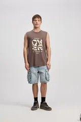 Musculosa oversize de algodón color marrón con efecto lavado desgastado, de corte amplio y sin mangas. Cuenta con una estampa frontal en relieve y diseño urbano de la marca Mistral.