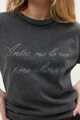Remera negra de algodón con efecto lavado, manga corta y cuello redondo. Presenta una estampa frontal con la frase escrita en letras brillantes de estilo cursivo.