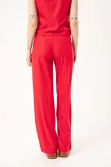 Pantalón rojo de lino imperial con lurex, tiro medio, corte recto, bolsillos delanteros y traseros, cierre frontal con cremallera y botón.