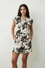 Blusa sin mangas color crema con estampado floral grande en negro y detalles en naranja. Presenta cuello en V con botones y corte holgado.