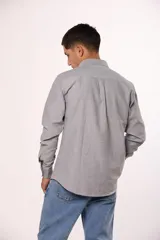 Camisa de manga larga en color gris, confeccionada en algodón, con cuello abotonado y cierre frontal de botones.