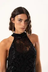 Vestido largo de encaje negro con destellos de lurex, diseño de cuello halter y tajos laterales. Incluye un vestido corto removible como forro interno.