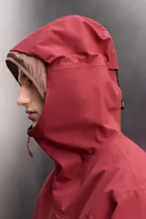Cazadora deportiva de esquí con diseño bicolor en tonos negro y verde oliva. Presenta capucha amplia con visera, cierre frontal con cremallera termosellada, bolsillos frontales y en manga con cierres impermeables, y aberturas de ventilación en las axilas. Incluye faldón interior antinieve, puños ajustables y tecnología de rescate RECCO.