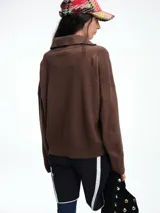 Sweater de punto color verde oliva, con cuello polo abierto en V, manga larga con hombros caídos y terminaciones acanaladas en puños y ruedo.