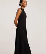 Vestido midi evasé color negro, sin mangas, con cuello redondo y tirantes anchos. Confeccionado en bengalina con costuras verticales decorativas.