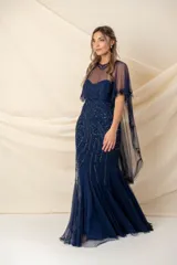 Vestido largo de fiesta color azul, confeccionado en tul bordado con diseño strapless. Incluye una capa tipo poncho de tul transparente con detalles bordados a juego, que cubre los hombros y cae hacia la espalda.
