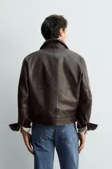 Cazadora de corte cropped confeccionada en piel con acabado napado y costuras efecto vintage. Presenta cuello solapa, cierre frontal con botones, mangas largas con puños abotonados y bolsillos laterales de vivo.