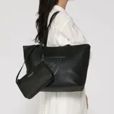 Cartera tipo tote bag Guess modelo Keira, color negro con textura saffiano, doble asa superior y logo triangular frontal en relieve. Incluye un pequeño neceser desmontable con cierre y inscripción de la marca.