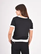 Remera de algodón en color negro con detalles en blanco en el cuello, mangas y ruedo. Presenta un diseño de estilo ringer con terminaciones acanaladas.