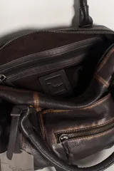 Cartera de cuero color negro con efecto lavado y desgastado, estilo vintage. Cuenta con múltiples bolsillos con cierre delantero, tiras colgantes y doble asa corta de mano.
