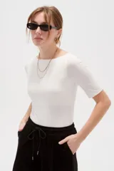 Remera de poliamida color blanco, de corte ajustado al cuerpo, con mangas 3/4 y cuello redondo a la base.