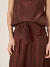 Falda midi color bordó con brillo sutil y detalle de lazo en la cintura.