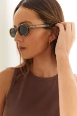 Lentes de sol con armazón ovalado de color negro y cristales tonalidad marrón. Presentan un detalle metálico en forma de estrella en las patillas.