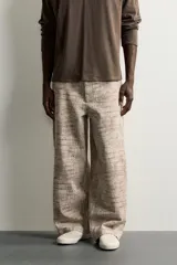 Pantalón relaxed fit de algodón con estampado animal print de cocodrilo en tonos beige y gris. Tiene diseño de cinco bolsillos, cierre frontal con cremallera y botón, y una tira con bolsillo multifunción en la pernera.