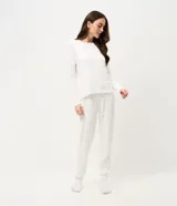 Pijama de dos piezas confeccionado en tejido de punto acanalado color blanco con estampado de pequeñas cerezas. Incluye una blusa de cuello redondo y manga larga, y un pantalón con cintura elástica y puños ajustados en los tobillos.