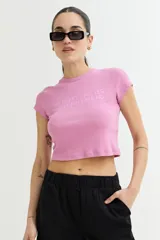 Remera crop top de manga corta, color rosa, con cuello redondo y tejido acanalado. Presenta un texto bordado en el pecho que dice "MY HEART SAYS YES MY BRAIN SAYS NO".