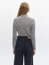 Polera azul de tejido suave con cuello alto y manga larga. Tiene un pequeño bordado en el frente y otro en la manga.