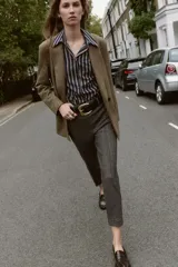 Pantalón de tiro alto con diseño de espiga, corte recto y nervio marcado en el frente. Incluye un cinturón ancho con hebilla metálica dorada y cierre lateral con cremallera oculta.