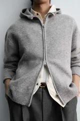 Chaqueta de punto con capucha, corte relajado, manga larga, bolsillos laterales y cierre frontal con cremallera. Presenta acabados en rib en puños y bajo.