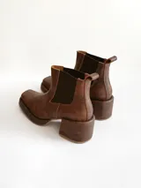 Bota tipo chelsea de cuero color chocolate con acabado texturizado, plataforma y taco cuadrado. Presenta paneles elásticos laterales en color negro.