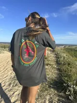 Remera color crema de algodón con estampa en la espalda de un paisaje playero con el texto "Chema Sure Chate et la mer".