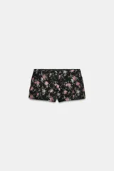 Shorts mini de tiro medio confeccionados en tejido jacquard con estampado floral sobre fondo negro. Presenta forro interior y cierre lateral con cremallera oculta.