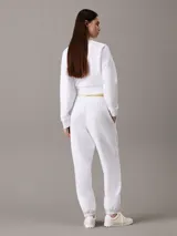 Pantalón de jogging blanco de felpa de mezcla de algodón, con cintura elástica con cordón ajustable, bolsillos laterales, bajos de canalé y monograma CK en la pierna. Corte tapered y largo estándar.