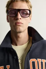 Sobrecamisa de ajuste relajado en color azul marino, con cuello de solapa, manga larga con puño abotonado y cierre frontal con botones. Presenta bordados contrastantes en el frente con la inscripción "St. Louis Worldwide Goods" en tonos naranja y blanco.