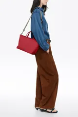 Bolso de mano Bimba y Lola de tamaño mediano, con estructura blanda, doble asa de mano y asa regulable de tejido. Cuenta con cierre de cremallera, detalles metálicos y logo de la marca en el frente.