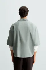 Camisa de corte relajado confeccionada en tejido mezcla de lyocell, con cuello solapa, manga corta y cierre frontal con botonadura oculta.