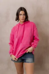Canguro oversize fucsia con efecto washed, capucha con cordones ajustables al tono, bolsillo frontal tipo canguro y terminaciones de rib en puños y cintura.