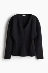 Top negro de tejido suave con efecto neopreno, escote en V, hombros caídos y mangas largas con puños ceñidos. Presenta una cintura entallada que realza la figura.