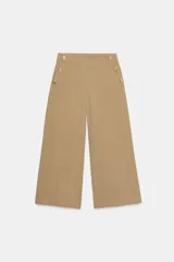 Pantalón tipo culotte de tiro alto, con pernera ancha y corta. Presenta detalles de botones dorados decorativos en la parte frontal y cierre lateral con cremallera oculta.