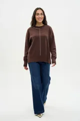 Buzo de punto color marrón con cuello redondo y detalle de costura vertical en contraste color blanco. Presenta mangas largas con puños acanalados y un corte relajado con aberturas laterales en el ruedo.