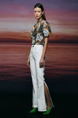 Pantalón de jean blanco, de tiro alto, corte flare y abertura lateral en la pierna.